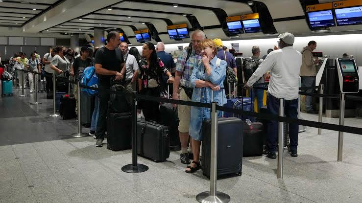 Cestující v letištním terminálu čekají na hraniční kontrolu